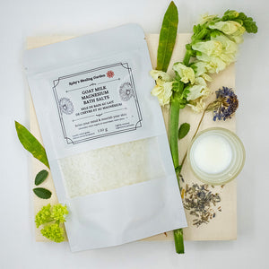 "Goat Milk Magnesium Bath Salts" surrounded by a glass of milk and leaves.